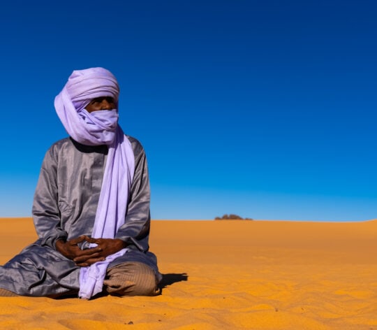 Tuareg sit in the Sahara desert, North Africa, Erg Admer, Algeria