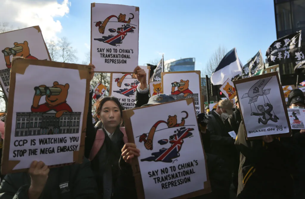 A protester among a sea of signs holds a sign saying ‘Say