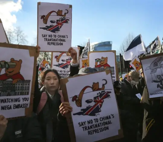 A protester among a sea of signs holds a sign saying ‘Say