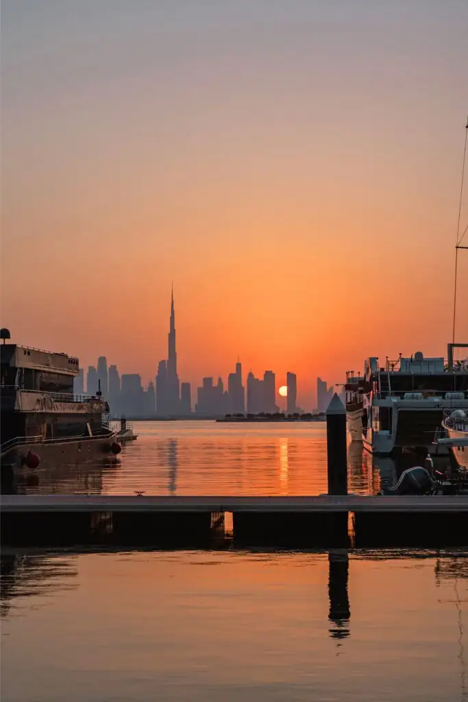 Golden sunset over Burj Khalifa and Dubai Downtown skyline, seen from Dubai Creek Harbour Marina with yachts