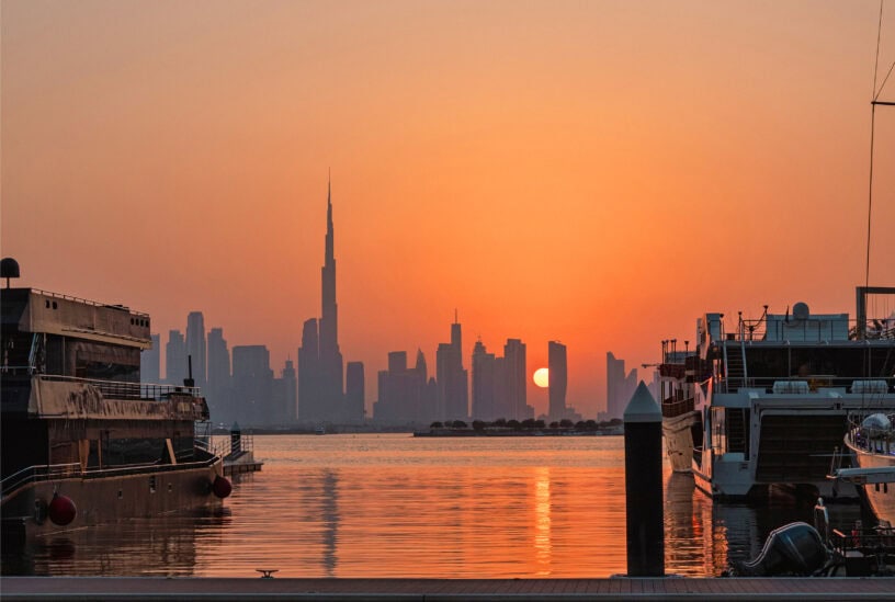 Golden sunset over Burj Khalifa and Dubai Downtown skyline, seen from Dubai Creek Harbour Marina with yachts
