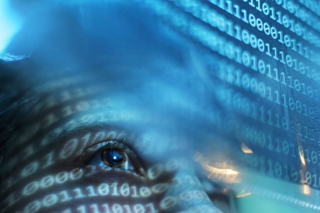 Portrait of woman looking on blue screen lit with binary code