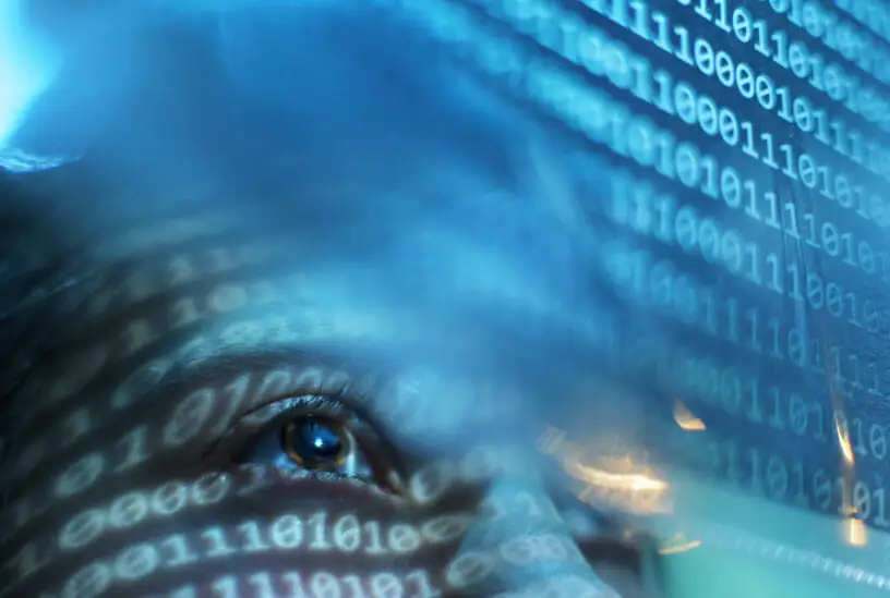 Portrait of woman looking on blue screen lit with binary code